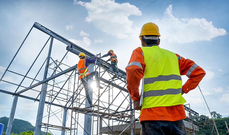 Cetan Funds aids in Commercial Construction Engineer technician watching team of workers on high steel platform
