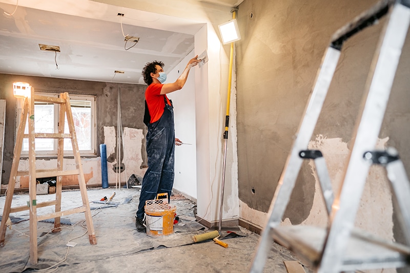 Cetan Funds provides Fix and Flip Rehab Loans Construction worker plastering and smoothing concrete wall